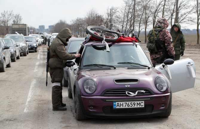2022年3月17日、現地住民が包囲されたウクライナの南方港湾都市マリウポリを離れる際、車を検問する親ロシア軍。（ロイター）