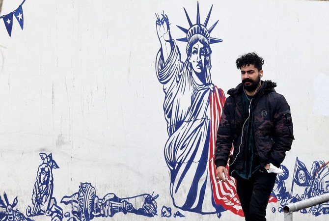 2022年3月12日、イランのテヘランにて、反米アートが描かれた壁の横を通り過ぎる男性。（AFP）