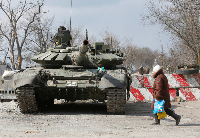 2022年3月18日、ウクライナの包囲された南部港湾都市マリウポリで、ウクライナとロシアの紛争中に親ロシア軍の戦車のそばを通り過ぎる現地住民。（ロイター/アレクサンドル・エルモチェンコ）
