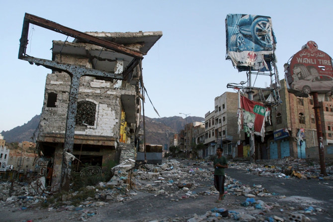 イエメン南西部のタイズ市で、戦闘によって破壊された建物の前を歩く男性。（ロイター）