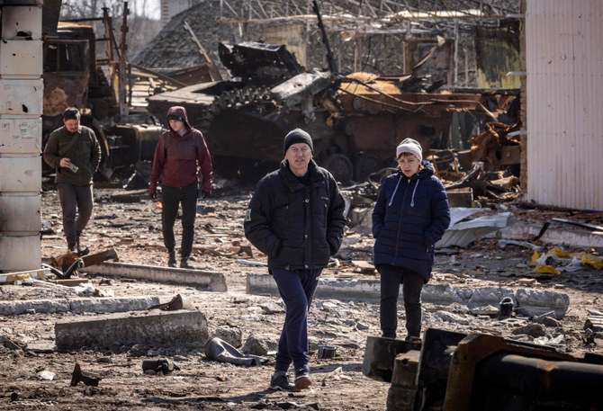 2022年3月29日、ウクライナ北東部の都市トロスチャネッツで、破壊されたロシア戦車付近の瓦礫の中を歩く住民たち。（AFP）