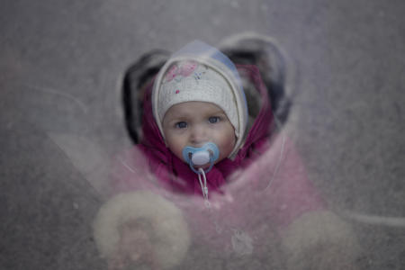 隣国のウクライナから戦争を逃れた子供が、2022年3月9日水曜日、ポーランドのプシェミシルにあるバスの窓から見ている。(AP)