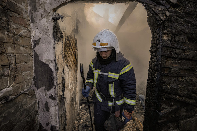 2022年3月23日水曜、ウクライナのキエフで爆撃により破壊された家屋の残骸の中に立つウクライナの消防隊員。（AP）