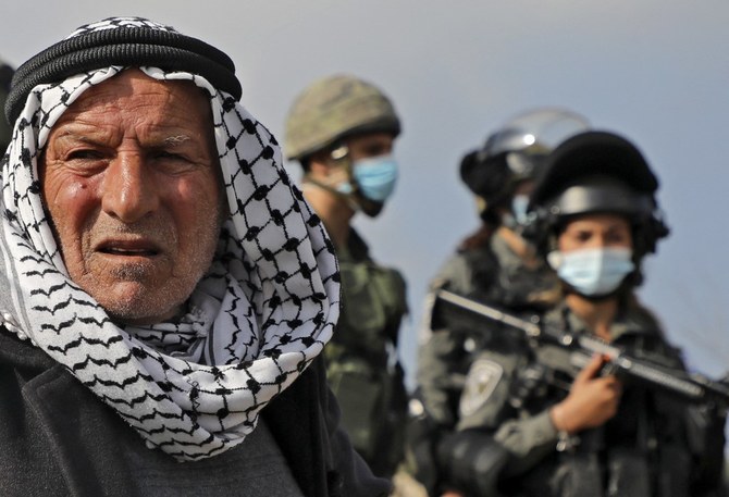 2020年12月22日、占領下のヨルダン川西岸地区中心部サルフィットの西にあるイスラエルの前哨入植地近くで行われたイスラエルの占領に反対するデモの最中、イスラエルの国境警備隊の前に立つパレスチナ人デモ参加者。（資料/AFP通信）