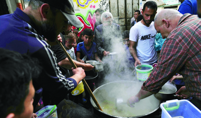 ガザ市、シュジャイヤ地区で断食前に温かい小麦スープとお粥を受け取る人々。(AP)