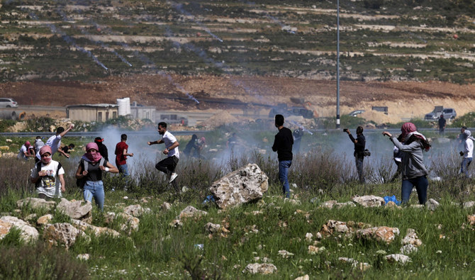 ヨルダン川西岸地区のイスラエル人入植地ベイト・エルに近いラマッラー北部の入口でのイスラエル治安部隊と衝突で、催涙弾から逃げ惑うパレスチナ人。（AFP／ファイル）