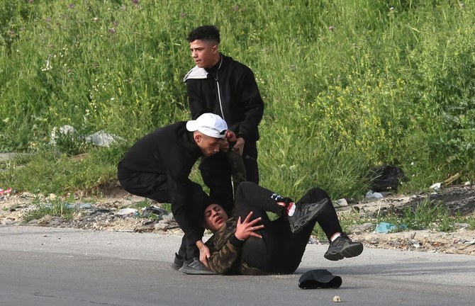 占領地ヨルダン川西岸の都市ナブルスで、指名手配中のパレスチナ人を捜索するイスラエル治安部隊と衝突して怪我をした青年を助けるパレスチナ人たち。（AFP通信）