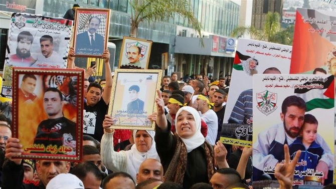 ヨルダン川西岸地区にある都市ナブルスで行われたパレスチナ人囚人デーを記念する集会で、イスラエルの刑務所に収容されている親族の写真を手にするパレスチナ人たち。(ロイター)