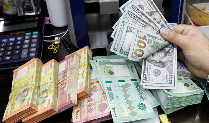 レバノンのベイルートにある両替店で、レバノン・ポンドが置かれた机で米ドル紙幣を数える男性。（ロイター/ファイル・写真）