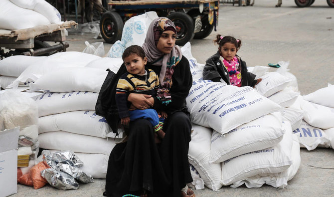 ガザ地区南部のカン・ユニス難民キャンプにある国連事務所で食料物資を受け取ったパレスチナ人女性が子どもと一緒に座っている様子。（AFPファイル写真）