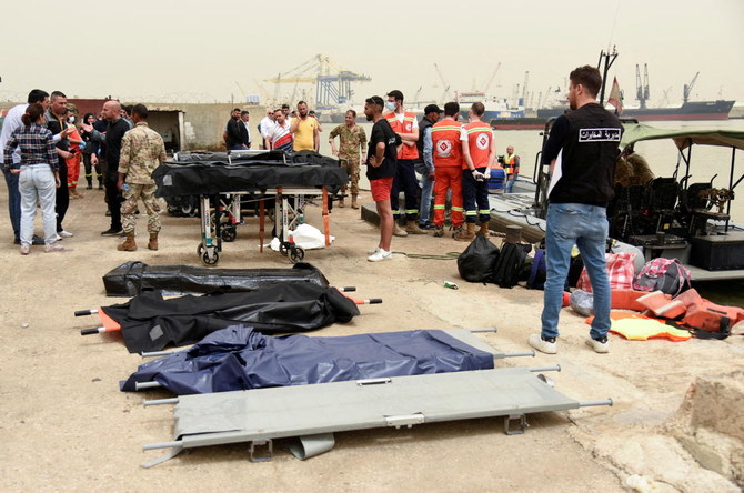 2022年4月24日、前夜にレバノンのトリポリ沖でボートが転覆した後、レバノン北部のトリポリ港で遺体のために用意された担架の近くに立つ人々。（ロイター）