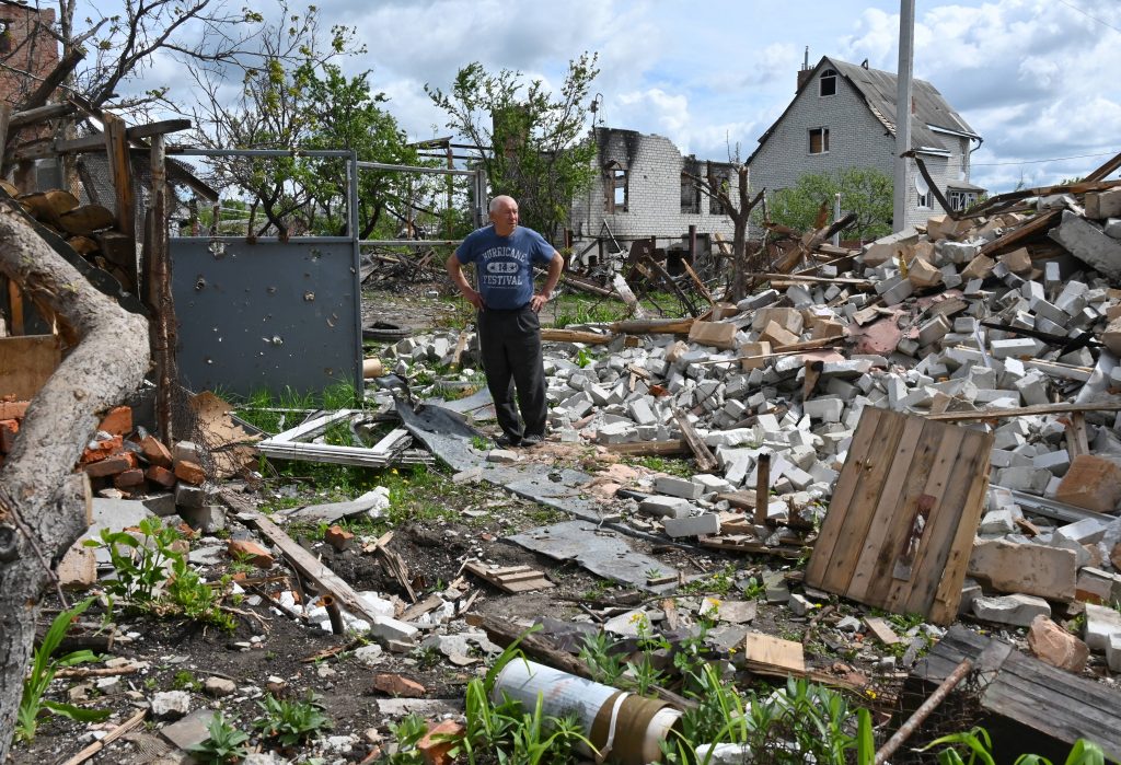 ロシアのウクライナ侵攻後、ウクライナ東部のハルキウ州マラゴーガンにある村で破壊された自分の家の庭のがれきに囲まれて現地の住人が立っている。2022年5月15日（AFP通信）