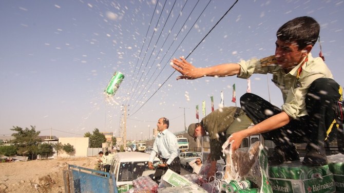 テヘランで没収されたラガー缶を捨てるイラン警察。イランではアルコールが禁止されている。（AFP）