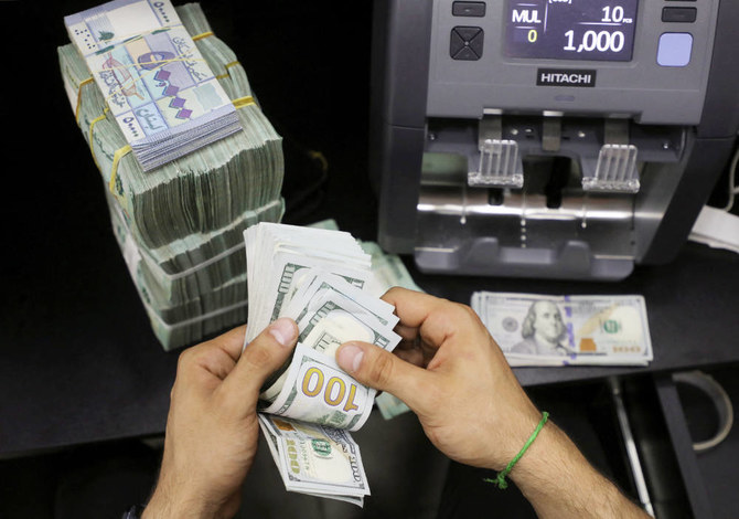 外貨両替店で、レバノンポンドの隣にある米ドル紙幣を数える両替商。2022年5月24日、レバノンのベイルート。（ロイター）