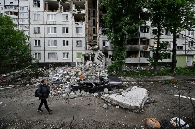 ハリコフ北部のサルチフカ地区で、甚大な被害を受けた住宅建物の前を歩く女性。（AFP通信）