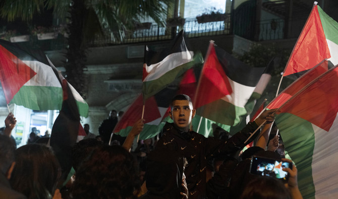 ベテランジャーナリスト、シリーン・アブアクラさんの実家の前でパレスチナの旗を振るデモ参加者たち。（AP）
