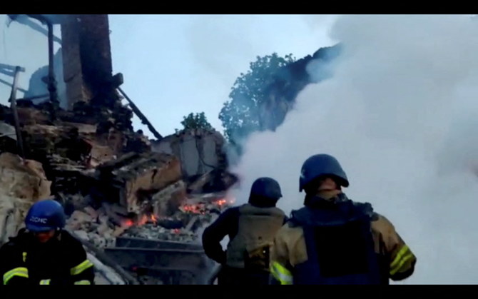 学校の建物が爆撃による被害を受けた後、燃える瓦礫のそばで火事に対応する救急隊員。2022年5月8日、ウクライナのルガンスクにあるビロホリフカ村にて。（ロイター）
