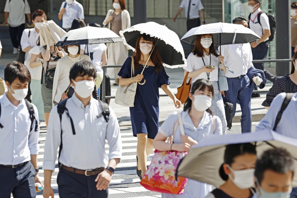 暑さに見舞われる中、東京で交差点を渡る人々。日傘を差している人もいる。（2022年6月27日）。（資料写真/AP）