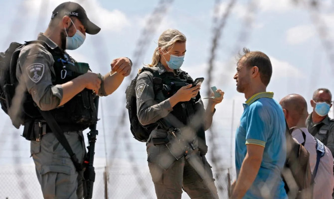 イスラエルで働くパレスチナ人労働者の書類を確認するイスラエル治安部隊。（AFP/File）
