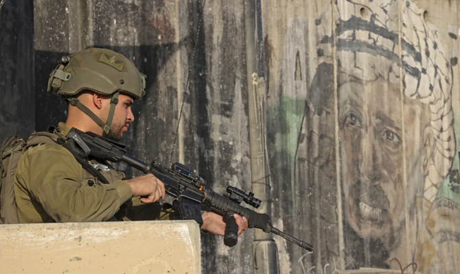 パレスチナ人たちが手続きを待つ占領下のヨルダン川西岸地区とエルサレムの間のカランディア検問所で、イスラエル兵士が警備に就いている。（AFP）