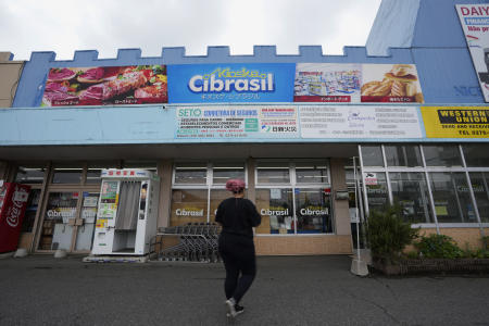 東京の北西約90キロ(55マイル)にある大泉町という町で、ブラジルで一般的に見られる食べ物や飲み物、商品を販売しているスーパーマーケットに向かって歩く女性。(AP)