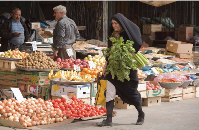 テヘランの南西50キロ（31マイル）に位置するエスラームシャフルの野菜市場でその日の買い物をして歩く女性。（ロイター）