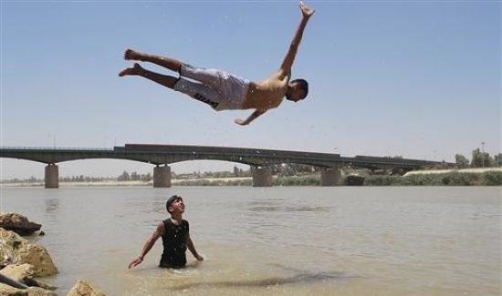 2009年7月1日、イラクのバグダッド北部にあるアダミヤ地区で泳ぐために、少年がチグリス川に飛び込んだ。（ロイター）
