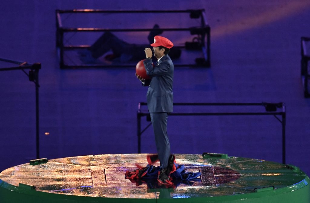 安倍元首相は赤い帽子をかぶって次に行われる大会を間違えないようアピールした。赤い帽子に書かれた文字には、こう書かれていた。「東京」と。（AFP）