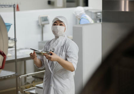 東京・千寿青葉中学校の調理室内で給食の献立を確認する栄養士の佐藤カズミさん=2022年6月29日、東京都千代田区。(ロイター)