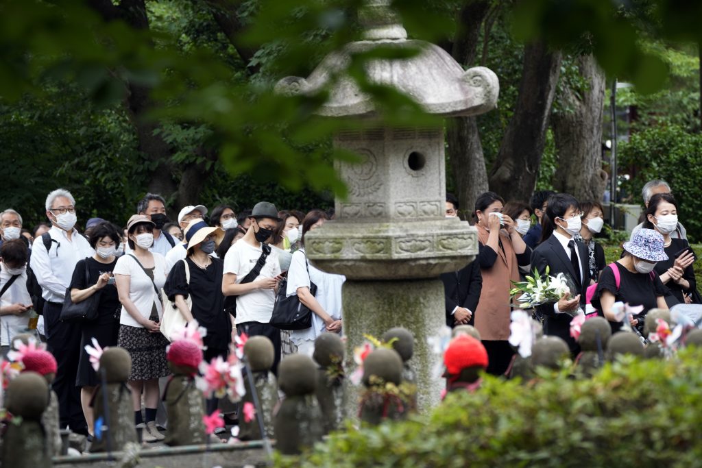 2022年7月12日火曜日、東京都の増上寺で、安倍晋三元首相の葬儀の前に、人々が花と祈りをささげるために列を作っている。安倍氏は8日、西日本の奈良県で街頭演説をしているときに暗殺された。（資料写真/AP）