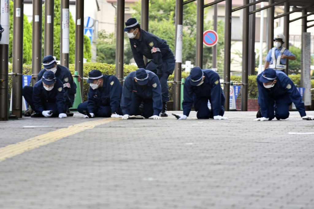 安倍晋三元首相が射殺された現場近くの歩道を調査する警察官=2022年7月13日、西日本・奈良県(File phoyo/Kyodo News via AP)