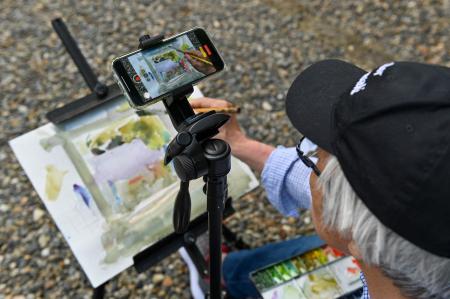 2022年5月25日撮影。千葉県いすみ市の神社で携帯電話を使って動画を撮影しながら水彩画を描く日本人アート講師の柴崎春通さん。（AFP）