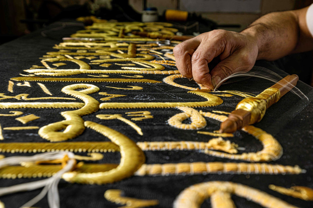 イスラム教の聖地メッカにあるグランドモスクのカアバ神殿を覆う布「キスワ」のレプリカに、イスラム教の聖典、コーランの一節を金糸で刺繍している刺繍職人。（AFP）