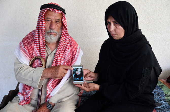 2022年6月27日、ガザ地区南部ハンユニスにあるバラカさん夫妻の自宅で、パレスチナ人のスレイマンさんとナズミヤさんが、殺された娘イスタブラク・バラカさんの写真を見せている。イスタブラクさんは昨年、夫に殺害された。（AFP）