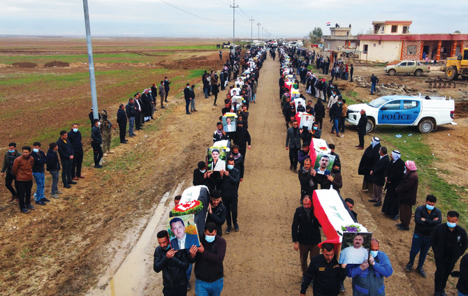イラク北部のシンジャール地区で行われた、ダーイシュ過激派の暴動により犠牲者となったヤジディ教徒の集団葬で、イラク国旗に包まれた棺を運ぶ弔問客たち。（2021年2月6日）（AFPファイル）