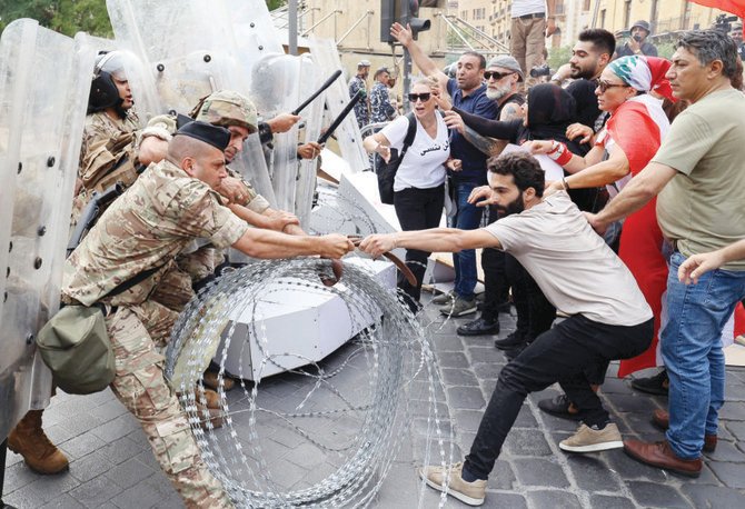 木曜日、ベイルート中心部で行われたデモで、国会議事堂の入り口を警備している兵士と対峙するレバノンの活動家たち。（AFP）