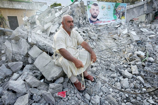 ヨルダン川西岸の都市ジェニン近郊のルンマナで、イスラエル軍に破壊された家の瓦礫に座るパレスチナ人。（AP）