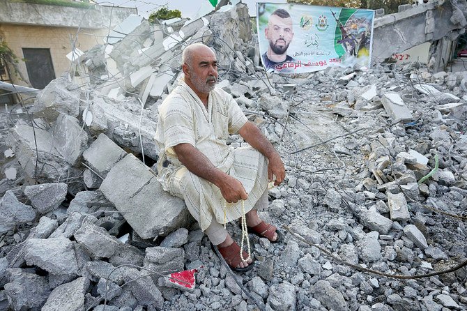 ヨルダン川西岸の都市ジェニン近郊のルンマナで、イスラエル軍に破壊された家の瓦礫に座るパレスチナ人。(AP)