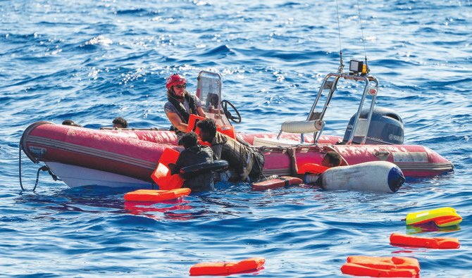 地中海で転覆した木製ボートに乗ろうとする移民を手伝う、救助活動中のNGO乗組員(AP)
