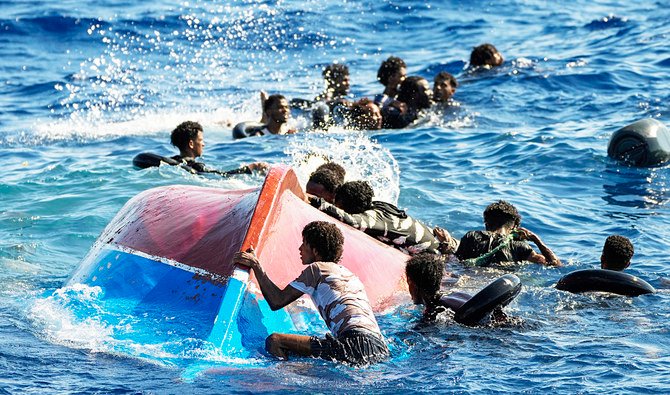 救助活動中に転覆した木製ボートの隣で泳ぐ移民たち。（AP）