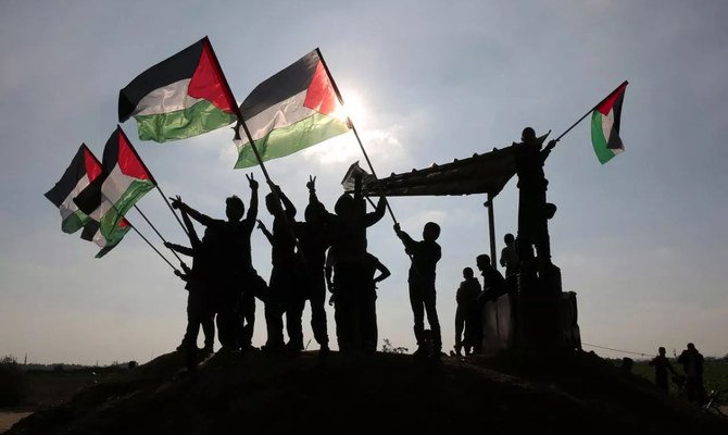 イスラエルとガザの国境付近でパレスチナ国旗を振るパレスチナのデモ参加者。（AFP/資料写真）