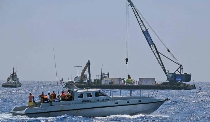 潜水艦の出発プラットフォームの傍を通り過ぎる、犠牲者親族を乗せたレバノン海軍の船舶。潜水艦は、4月に移民らを乗せたまま転覆した船を発見するために調達された。2022年8月22日、トリポリ。（AFP）
