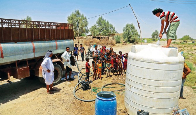 イラク中部ディワーニーヤ県のアル・アガワット村で、水不足と高温の中、タンクから水を得ようと集まる人々。（AFP）