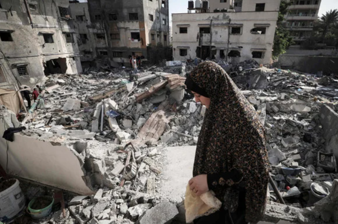 イスラエルとパレスチナ武装勢力の間の停戦成立後、ガザ市で自宅前のがれきの中を歩く女性（2022年8月8日早朝、AFP）