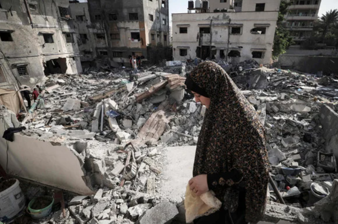 イスラエルとパレスチナ武装勢力の間の停戦成立後、ガザ市で自宅前のがれきの中を歩く女性(2022年8月8日早朝、AFP)