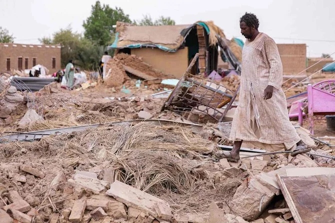2022年8月19日、スーダンのナイル川州のマカイラブ村で、洪水により倒壊した泥レンガの家の残骸を通り過ぎる男性。（AFP）