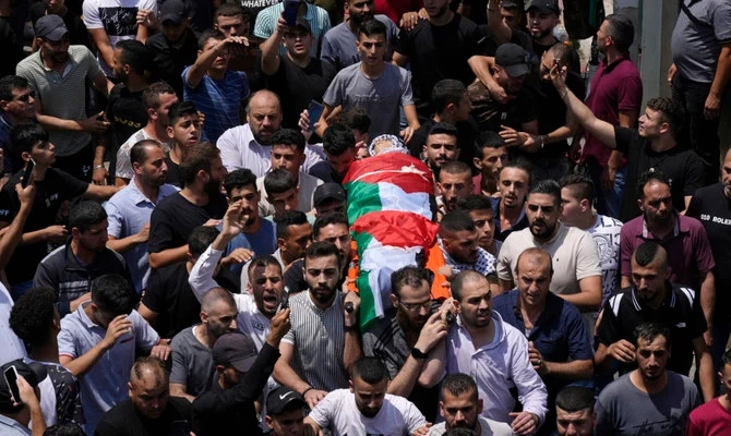 2022年8月9日火曜日、ヨルダン川西岸地区の町ナブルスで行われたフセイン・タハさん(15歳)の葬儀中、同少年の遺体を運ぶパレスチナ人。（AP通信）