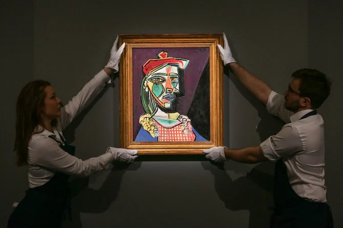 スペイン人画家パブロ・ピカソによる推定価格5000万ドルの作品「Femme au beret et a la robe quadrillee」（マリーテレーズ・ウォルター）を手にするギャラリーの職員たち。（AFP）