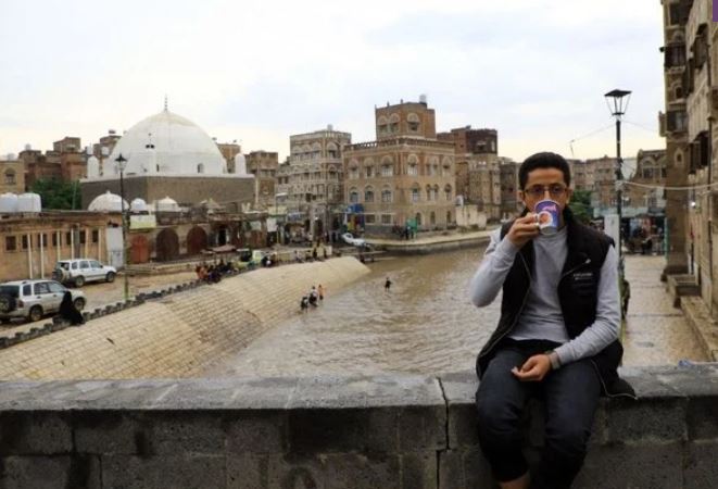 2022年8月1日、イエメンの首都サヌアの旧市街で、豪雨で冠水した道路を見下ろす橋の上でコーヒーを飲むイエメン人男性。（AFP）