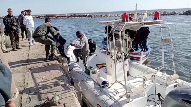 チュニジアのスファックス県ジベニアナで、移民の少年が救命ボートから降りるのを助けるチュニジアの沿岸警備隊員。（File/Reuters）